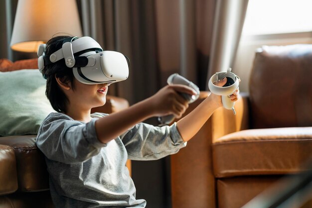 Ảnh miễn phí thoát khỏi trẻ em châu Á nam cậu bé thích chơi game metaverse với tai nghe vr đeo được có tay cầm điều khiển chơi game thể thao trực tuyến trong phòng khách ở nhà công nghệ gia đình thiếu niên trẻ sử dụng công nghệ vr